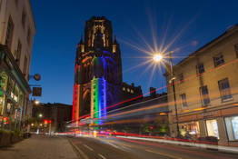 The Wills Memorial Building lit up in Pride flag colours, as seen from Park Street at night